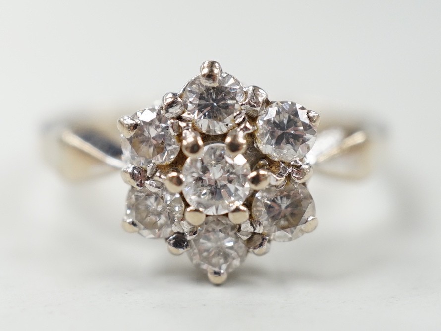 A modern 18ct white gold and seven stone diamond set hexagonal cluster ring, size O, gross weight 3.9 grams.